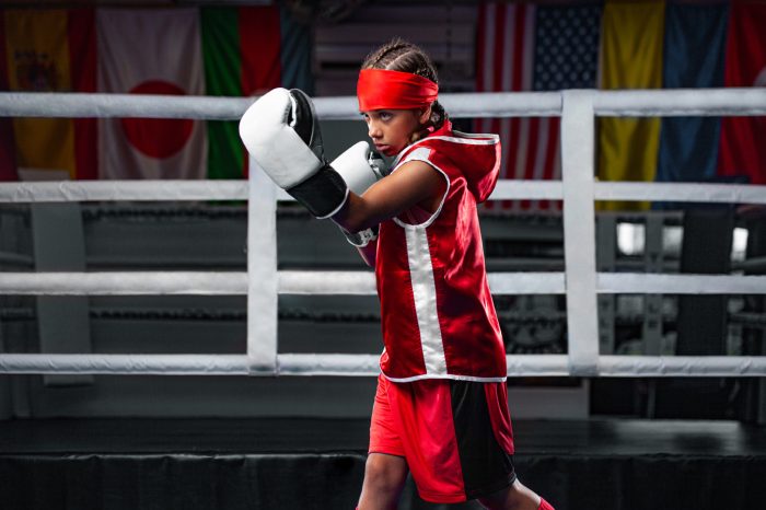 Kids sport concept. Girl sportsman muay thai boxer fighting in gloves in boxing gym.